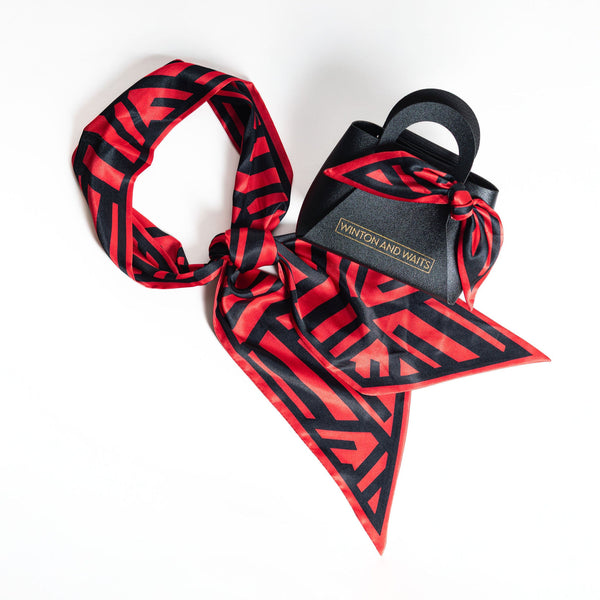 Red and black patterned scarf with a black bag on a white background
