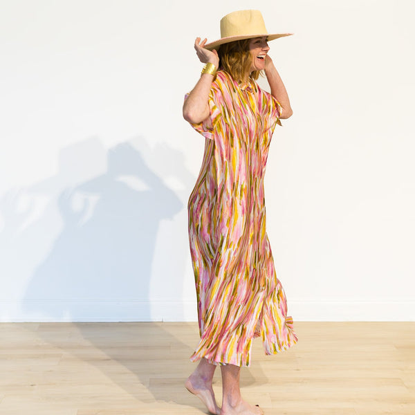 Woman wearing a colorful dress and straw hat on a white background