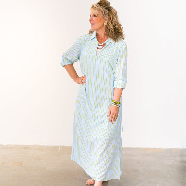Woman wearing a light blue striped dress standing on a wooden floor with a white background