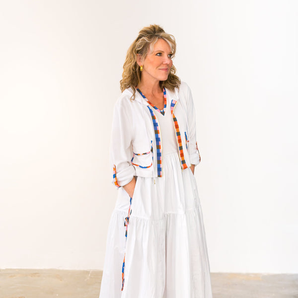 Woman wearing a white dress with colorful accents against a plain background
