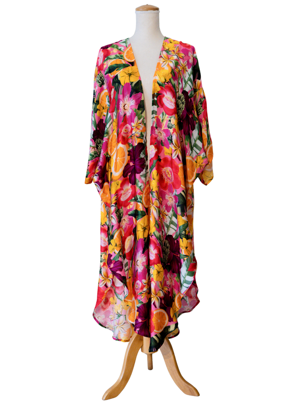A long-sleeve, open-front kaftan dress with a vibrant multicolor floral print, displayed on a wooden dress form mannequin against a plain white background.