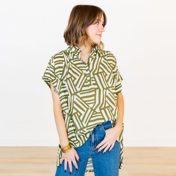 Woman wearing a green geometric patterned shirt and blue jeans on a white background