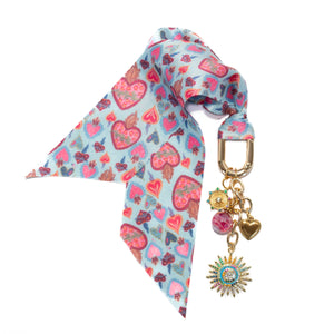 Scarf with heart pattern and keychain with charms on a white background