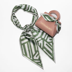 Green and white patterned scarf with a pink pouch on a white background