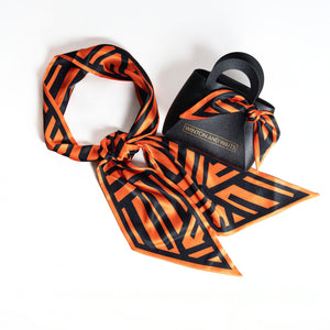 Orange and black patterned scarf with a black bag on a white background