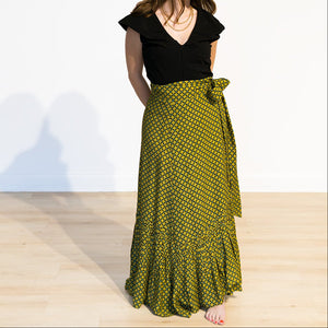 Woman wearing a black top and green patterned skirt on a white background