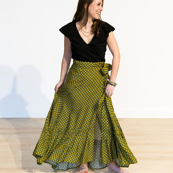 Woman wearing a black top and green patterned skirt on a white background