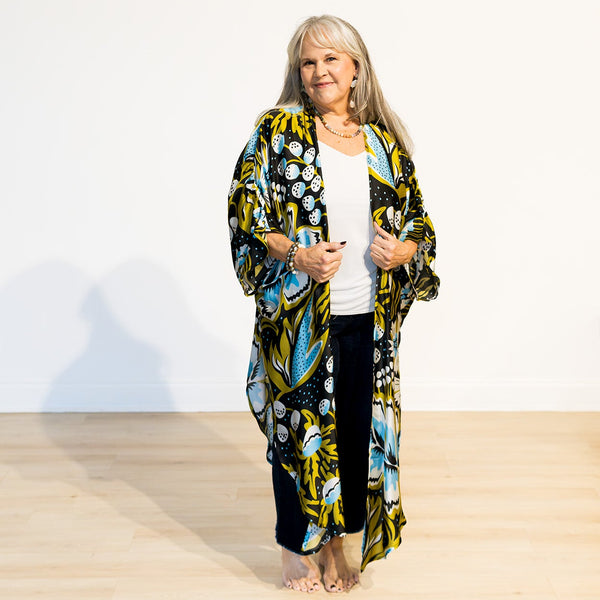 Woman wearing a colorful floral kimono-style garment on a white background