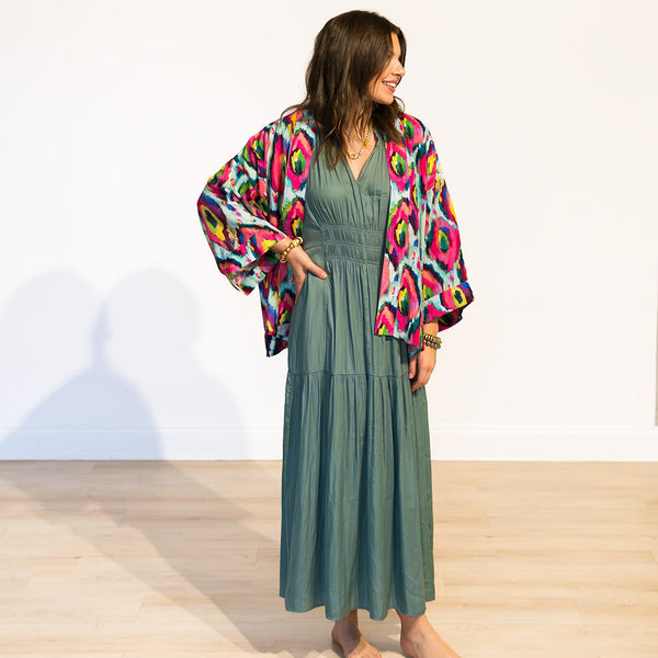 Woman wearing a colorful kimono over a green dress on a white background