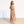 Woman wearing a colorful dress standing on a wooden floor with a white wall background