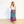 Woman wearing a colorful skirt and white top on a plain background