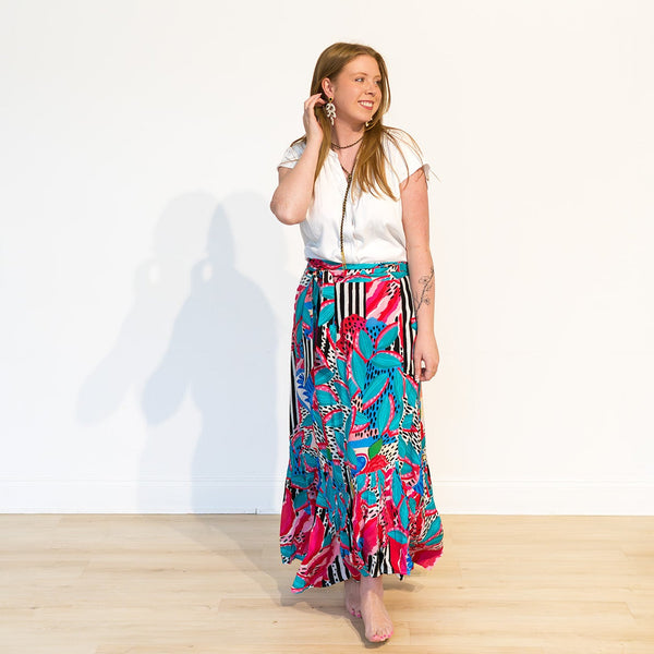 Woman wearing a colorful skirt and white top on a plain background