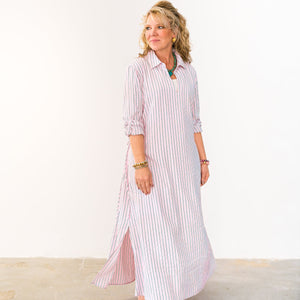 Woman wearing a long, light-colored dress with vertical stripes against a white background