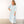 Woman wearing a light blue striped dress standing on a wooden floor with a white background