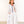 Woman wearing a white dress with colorful accents against a plain background