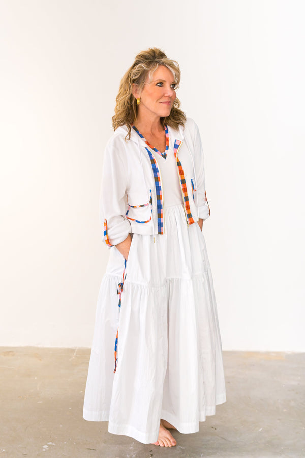 Woman wearing a white dress with colorful accents against a plain background