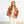 A woman stands against a plain white wall wearing a bright floral kimono-style jacket over a white top and white pants.