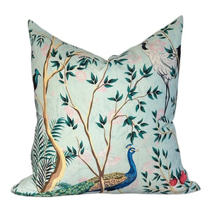 Decorative pillow with peacock and bird design on a light blue background