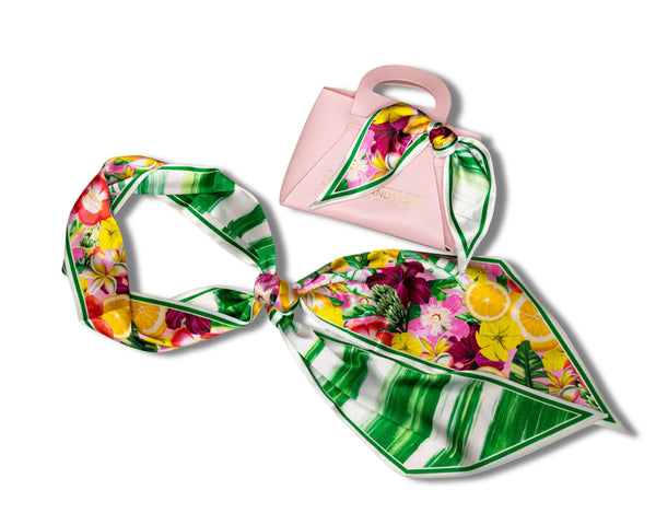 Colorful floral and striped scarf with a pink handbag on a white background