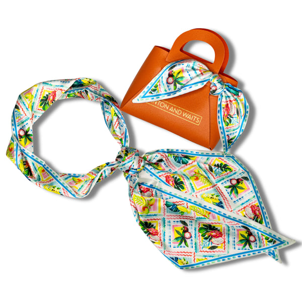 Colorful scarf with vintage-style design and an orange pouch on a white background